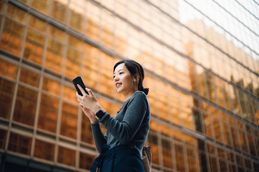 Woman on phone standing in front of a high rise building