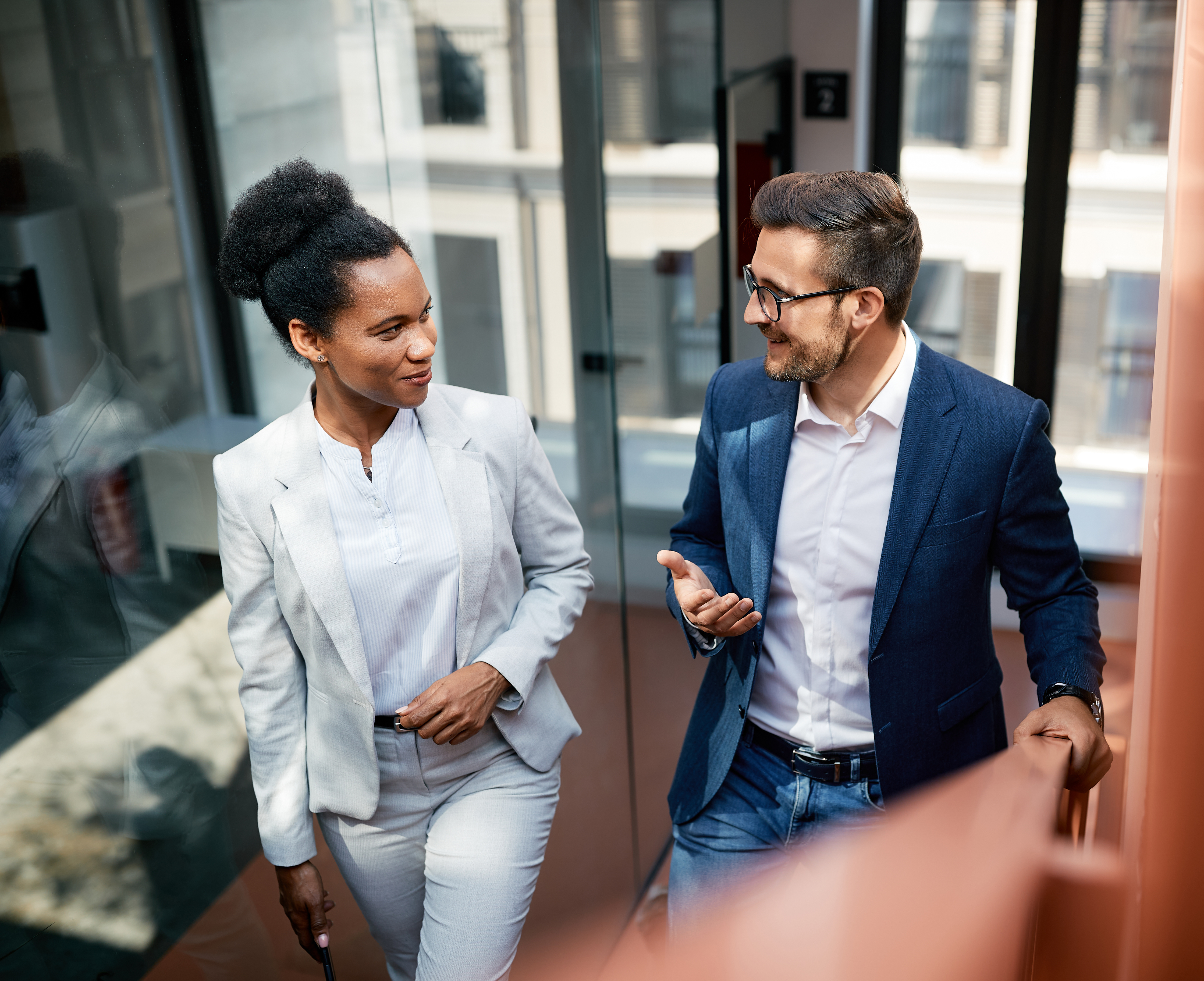 Professional woman and man walking up stairs talking