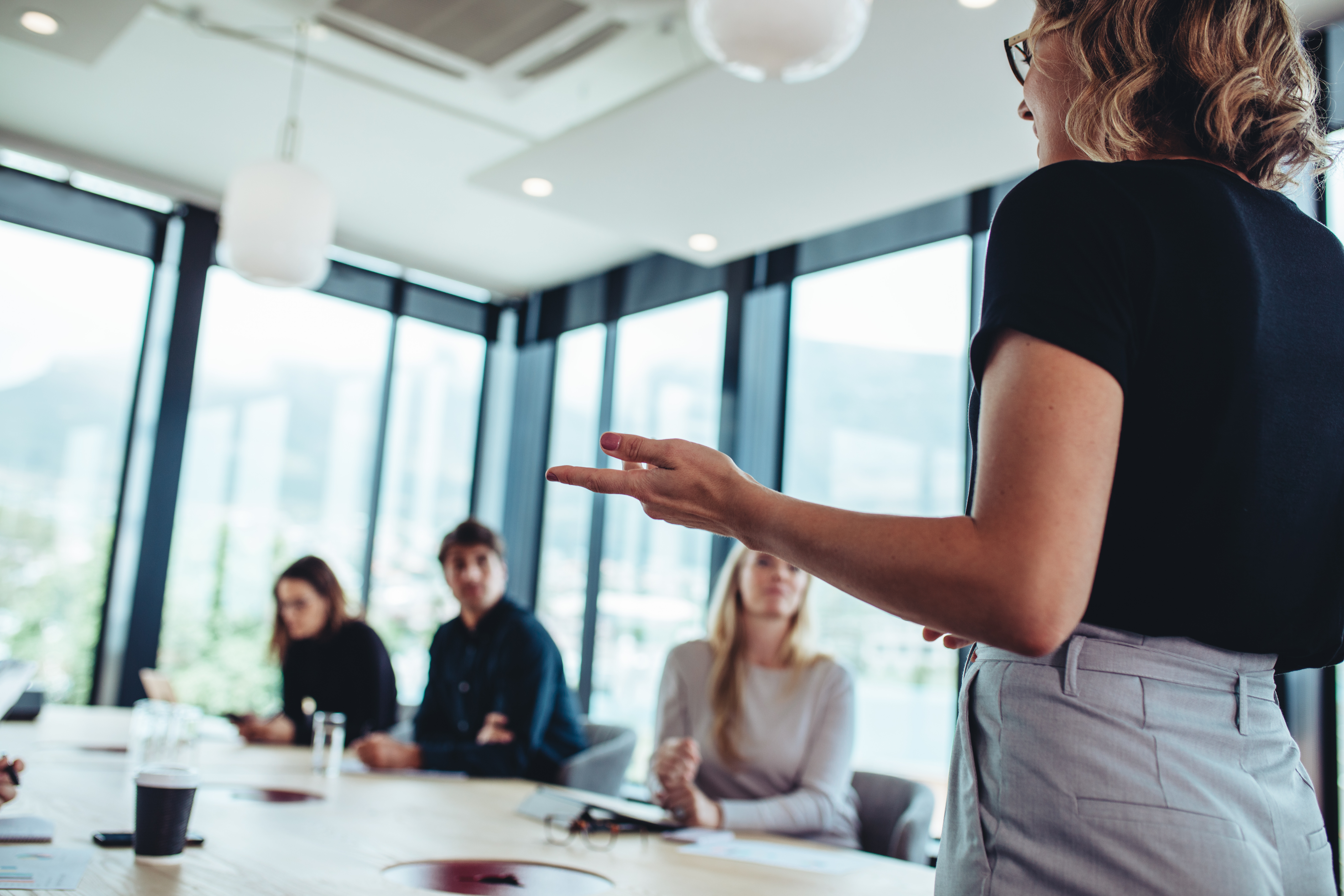 Depth of field image of a blond woman presenting to a conference room of people